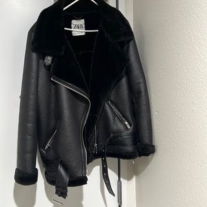 Oversized black faux leather jacket with fur collar and zippers